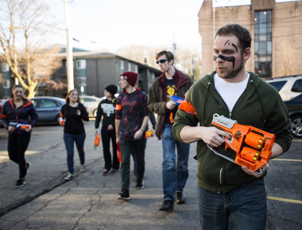 MSU alumnus Peter Matcheck leads a group of "humans" to a mission at Beaumont Tower on April 12, 2016 in Cedar Village. Matcheck and friends participated in Spartans vs. Zombies, a game founded in 2010. Spartans vs. Zombies is an advanced game of tag in which the goal as a human is to remain alive as long as possible by avoiding zombies. Humans are identified by a orange bandana wrapped around their arm, whereas zombies are identified by a orange bandana around worn on their head.