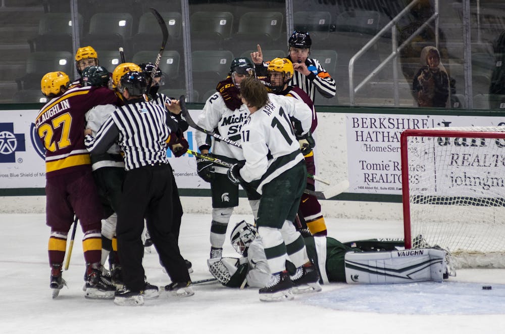 <p>Two referees break up a fight in the Spartan goal in the third period. The Spartans fell to the Golden Gophers, 3-1, on Dec. 3, 2020.</p>