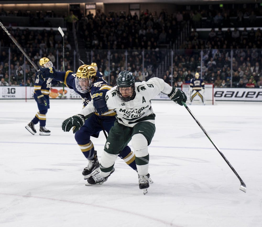 Michigan State University junior defense Matt Basgall (9) and Notre Dame senior forward Tyler Carpenter (28) race to the puck during the MSU vs. Notre Dame men’s hockey game on Nov. 16, 2024. 