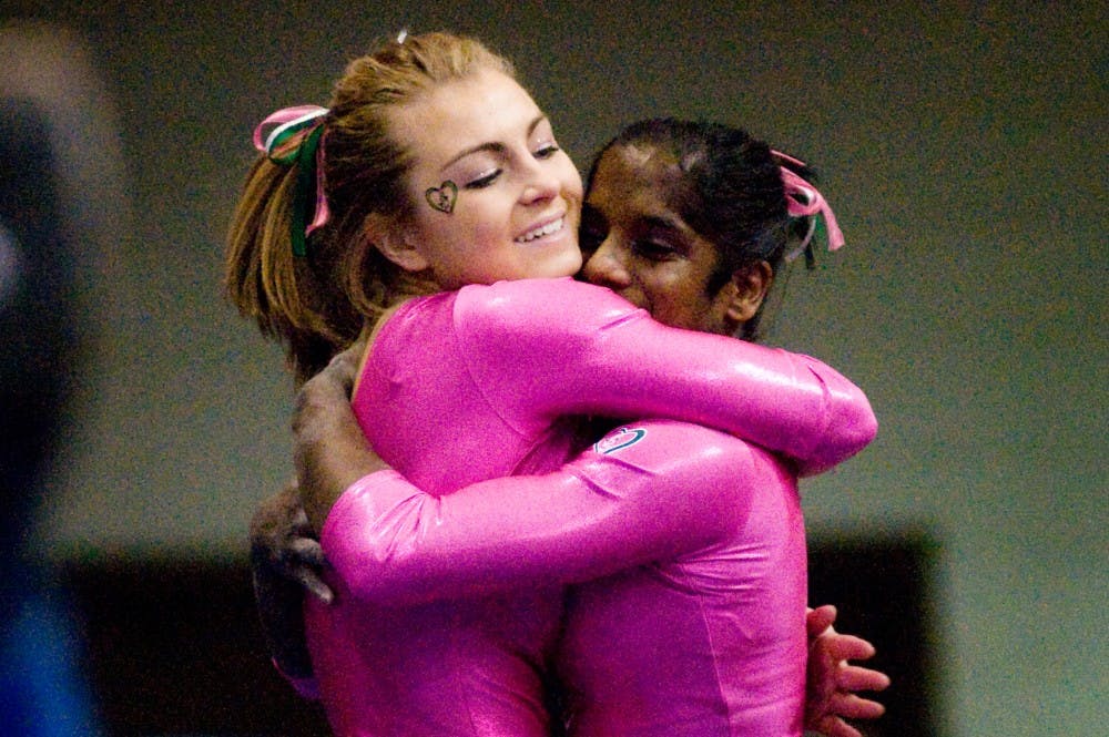 Sophomore Shanthi Teike, right, hugs freshman Alex Pace after Pace completed her balance beam routine during Saturday's meet against Minnesota at Jenison Field House. Lauren Wood/The State News