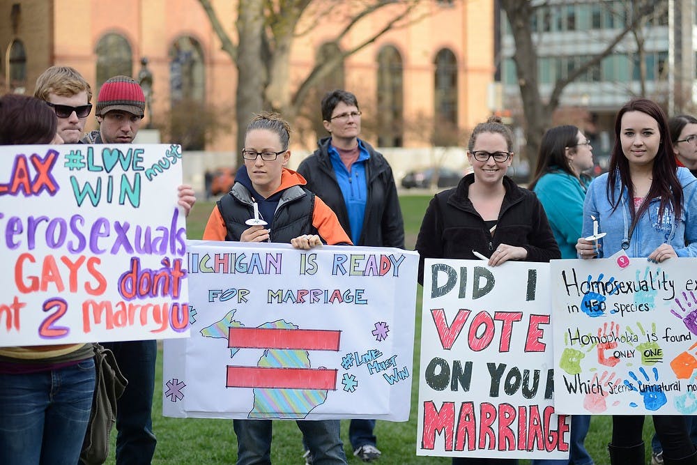 <p>From left, East Lansing residents Katie Ling, Alyssa Beavers and Taylor Young hold up signs to support same-sex marriage April 27, 2015, at the Lansing Capitol.The vigil was held in anticipation of the same-sex marriage trials in the U.S. Supreme Court. Hannah Levy/The State News</p>