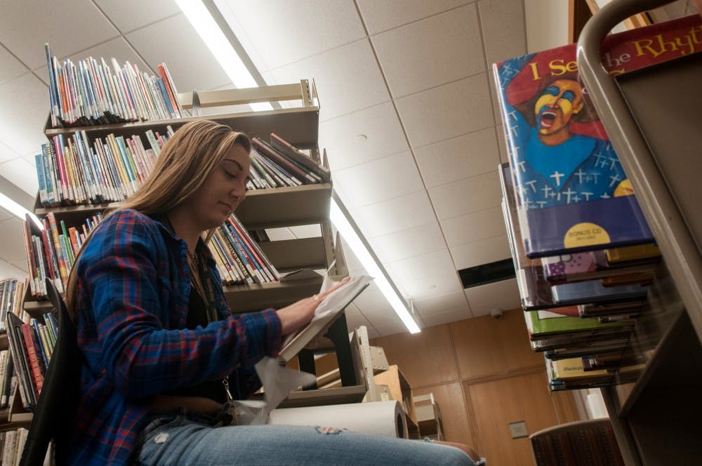 Education freshman Heather McArdle cleans books on Sept. 27, 2016 in the East Lansing Public Library at 950 Abbott Rd. McArdle volunteered her time to help prepare the library for its reopening after several months of renovations. 