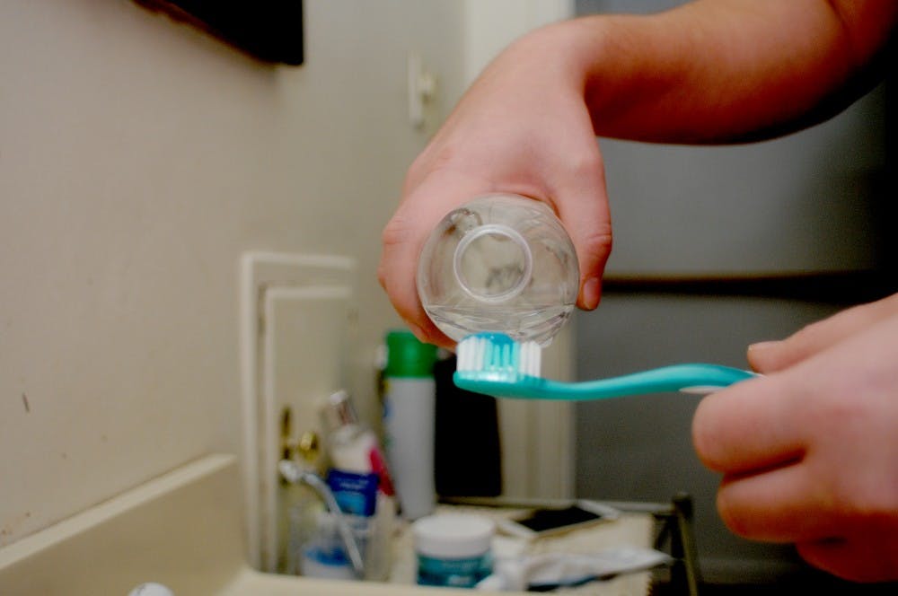 Interdisciplinary studies in social science senior Ricardo Vasquez demonstrates pouring bottled water onto his toothbrush on Feb. 12, 2016 at his home in Flint, Mich. Vasquez relies on bottled water to complete daily tasks since it isn't safe to use the tap water in his home. 
