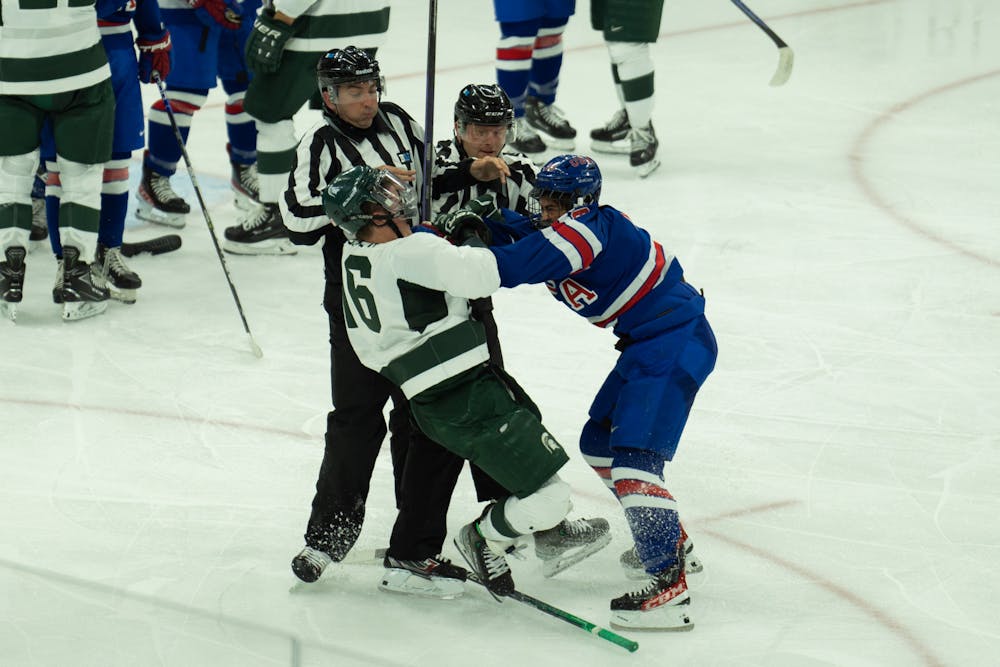 Sophomore center Jesse Tucker (16) fights with a member of the USNTDP at Munn Ice Arena on Oct. 1, 2022. The Spartans lost to the USNTDP 4-3.