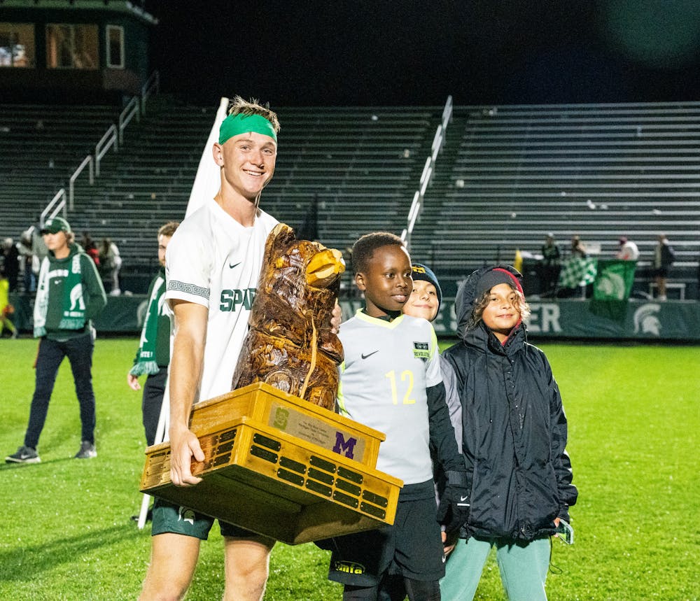 <p>Michigan State sophomore defender Josh Adam (14) poses with the Big Bear trophy with some kids at DeMartin Stadium on Sept. 27, 2022. Spartans defeated the Wolverines 2-0. </p>