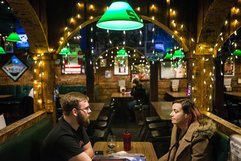 Lansing resident Eddie Dean, left, and East Lansing resident Beck Hosler, right, converse with one another during Portland, Mich. resident Russ Holcomb's performance on Feb. 1, 2017 at Crunchy's at 254 E. Grand River Ave. Crunchy's has various musicians play live music every Wednesday from 10 p.m. to midnight.
