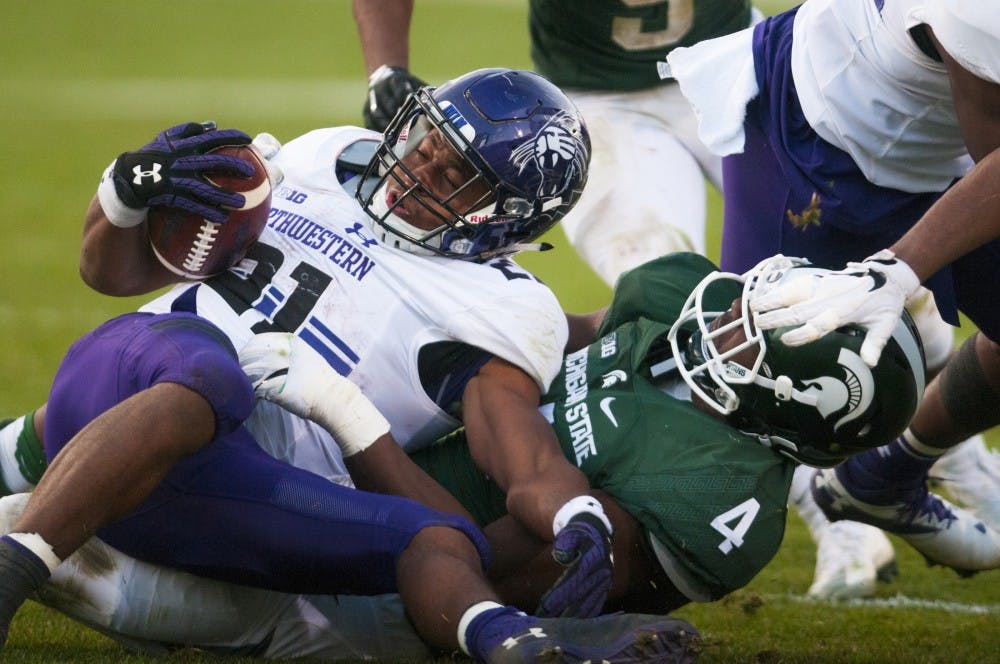 Junior defensive tackle Malik McDowell (4) tackles Northwestern running back Justin Jackson (21) during the game against Northwestern on Oct. 15, 2016 at Spartan Stadium.  The Spartans were defeated by the Wildcats, 54-40.  