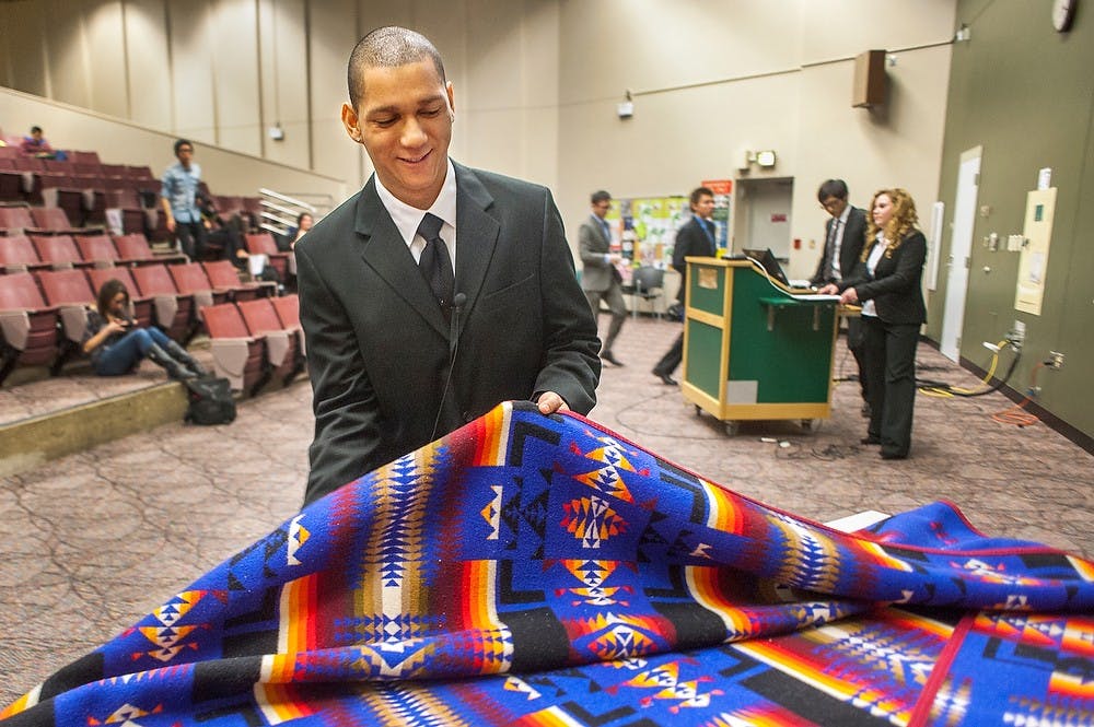 	<p>Marketing freshman Jonathan Wallace folds an American Indian blanket after his group presentation on Vine Deloria Jr. Wednesday night, Feb. 20, 2013, at Business College Complex.  Tthe Black History Month Multicultural Hero Hall of Fame Case Competition has been an annual event for the past 12 years. Justin Wan/The State News</p>
