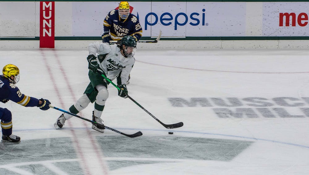 Junior Cole Krygier (8) successfully dodges two Notre Dame players as he gets the puck out of Michigan State territory. The Fighting Irish shutout the Spartans 2-0 on Feb. 27, 2021.