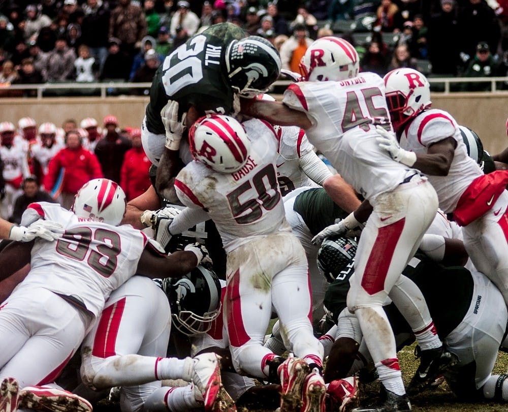 <p>Senior running back Nick Hill jumps over the pile of players to score a one-yard touchdown Nov. 22, 2014,  during the game against Rutgers at Spartan Stadium. The Spartans defeated Rutgers, 45-3. Erin Hampton/The State News.</p>