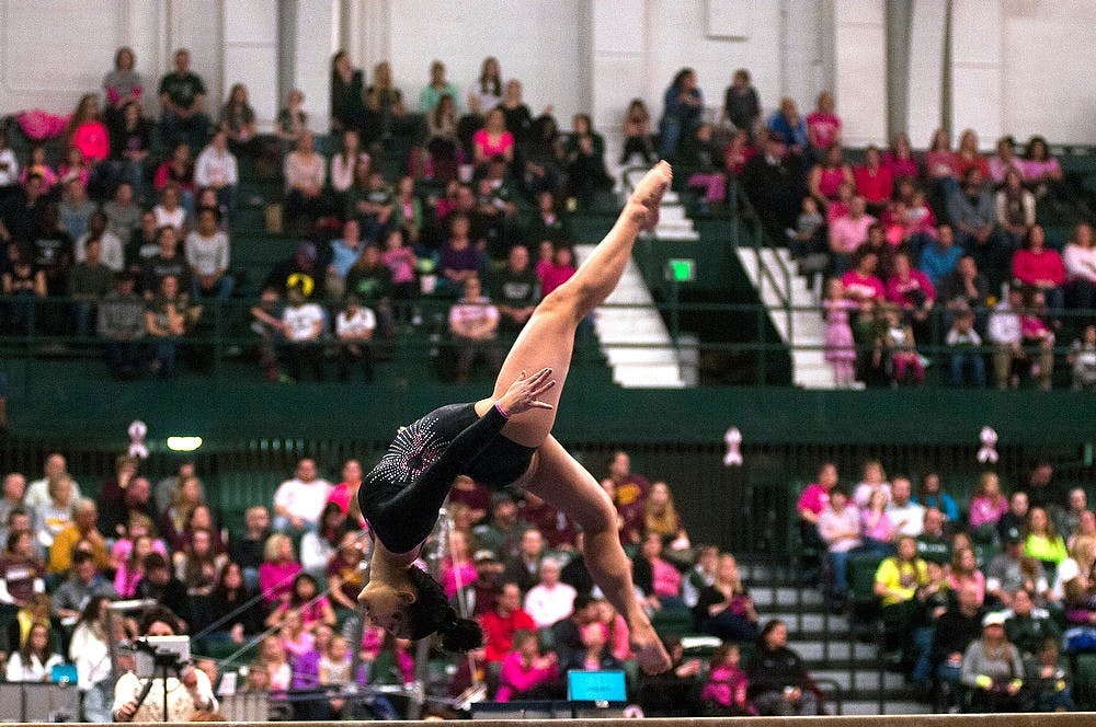 <p>Junior Lisa Burt performs on the beam Jan. 24, 2015, during the Breast Cancer Awareness meet against Minnesota at Jenison Field House. The gymnastics team lost with a score of 196.875-195.750. Hannah Levy/The State News</p>