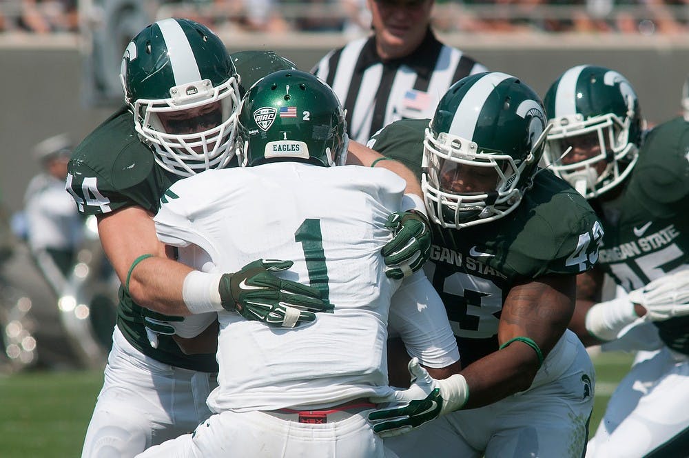 <p>Eastern Michigan quarterback Rob Bolden takes a hit from junior linebacker Ed Davis, 43, and senior defensive end Marcus Rush, 44, on Sept. 20, 2014, at Spartan Stadium. The Spartans defeated the Eagles, 7314. Raymond Williams/The State News</p>