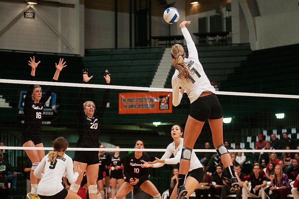 <p>Sophomore outside hitter Chloe Reinig spikes the ball as Nebraska setter Mary Pollmiller and middle blocker Meghan Haggerty attempt to block Oct. 10, 2014, at Jenison Field House. The Cornhuskers defeated the Spartans, 3-1. Aerika Williams/The State News</p>