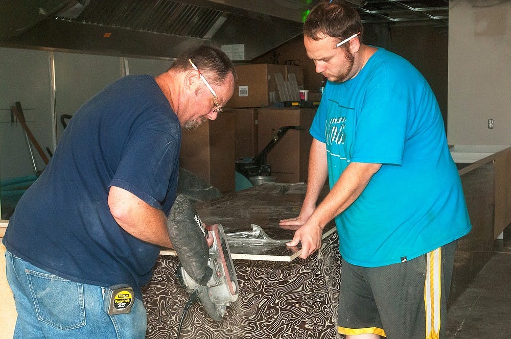 <p>From left, Milford, Mich., residents, Ed Starkey and Eddie Starkey work on construction at Sweet Lorraine's Fabulous Mac n' Cheez on July 30, 2014 on Grand River Avenue. The restaurant is scheduled to open sometime this August. Jessalyn Tamez/The State News</p>