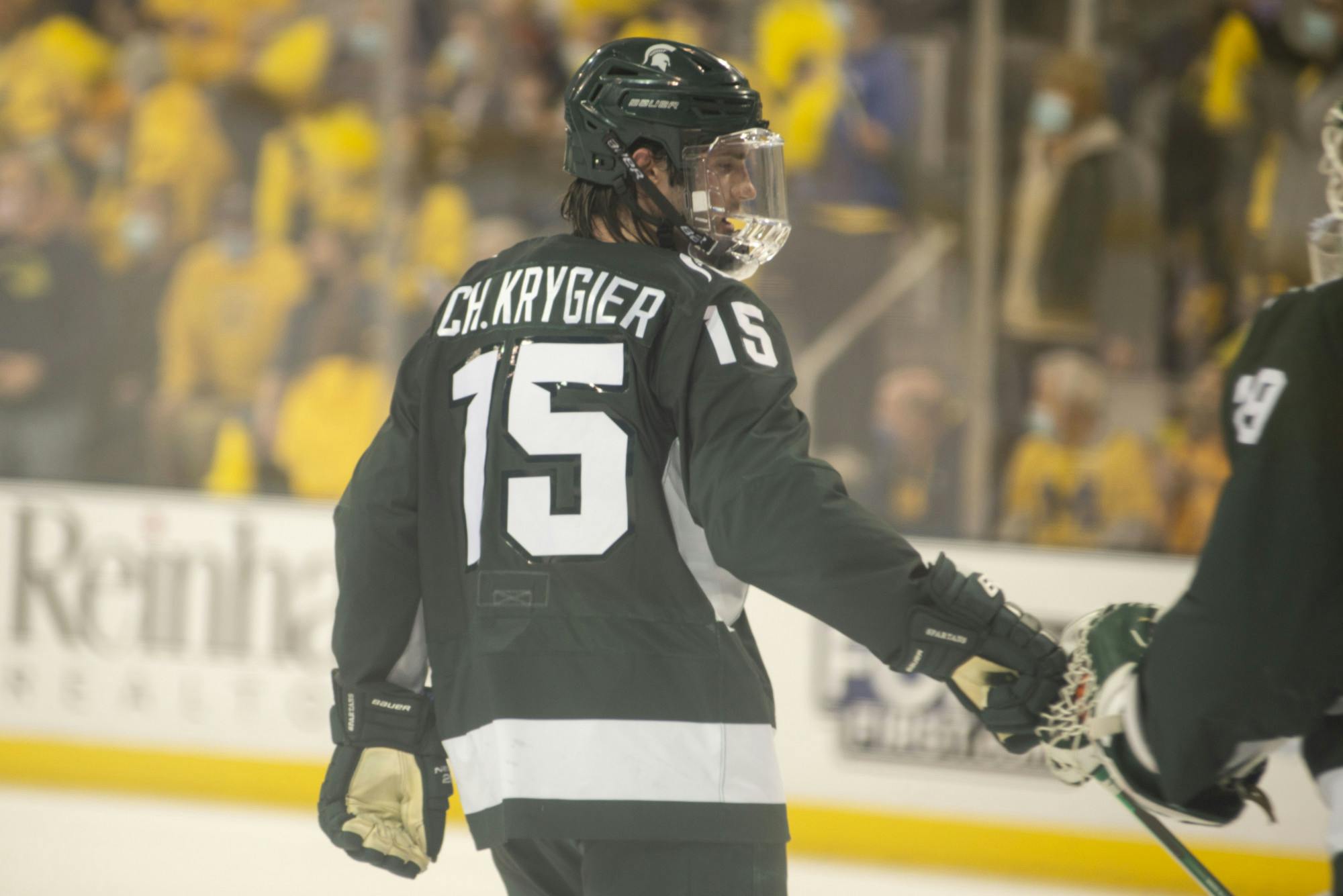 <p>Senior defenseman Christian Krygier (15) taps a fellow player during the game against Michigan on Nov. 5, 2021, at Yost Ice Arena.</p>