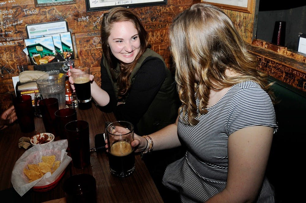 <p>Graduate students Claire Granskog, left, and Sarah Sheff enjoy drinks with friends March 29, 2014, at Crunchy's. Crunchy's is often know for its karaoke nights. Allison Brooks/The State News</p>