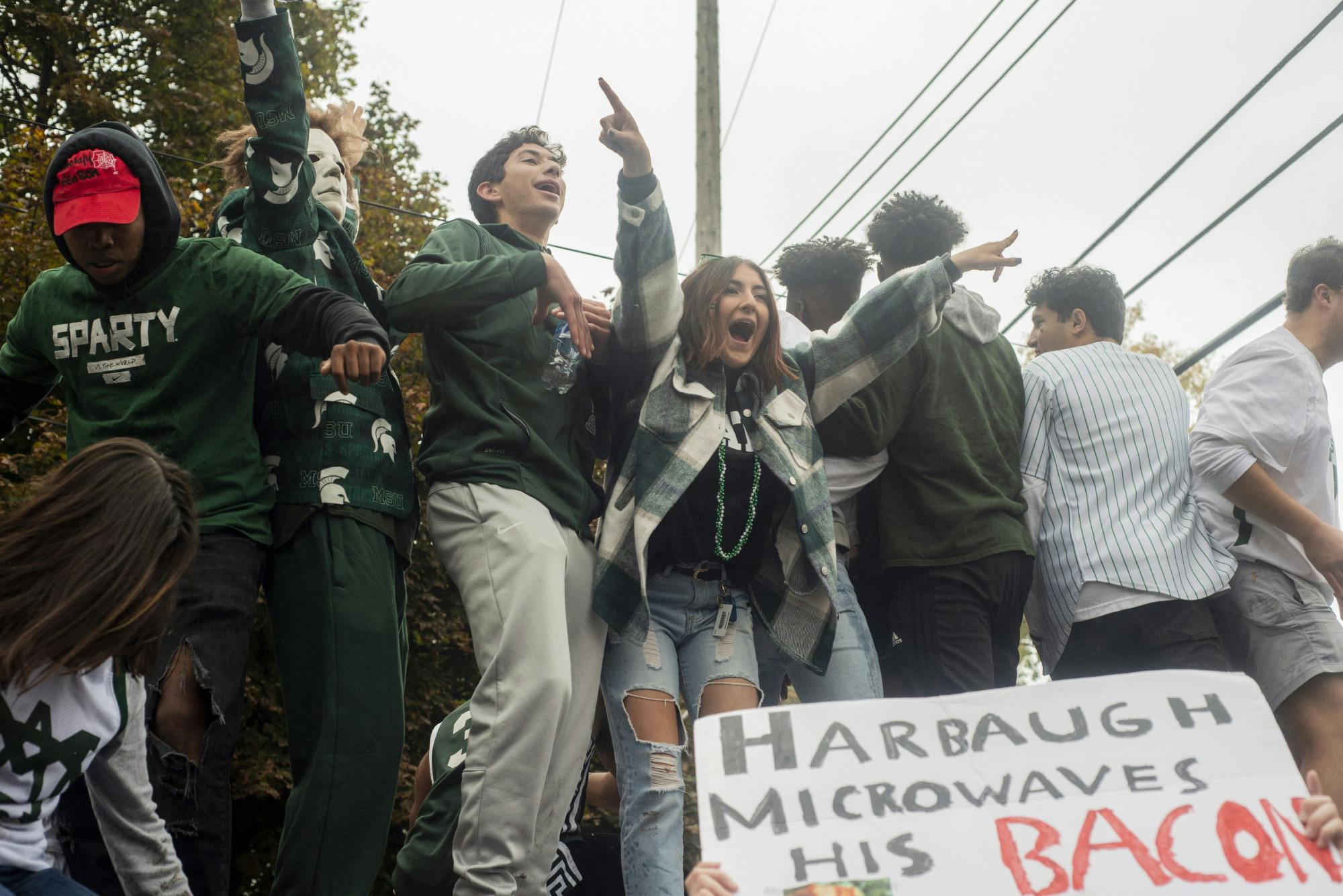 <p>People climbing and taking pictures on a flipped car at the Cedar Village apartments after MSU&#x27;s win against U-M on Oct. 30, 2021.</p>