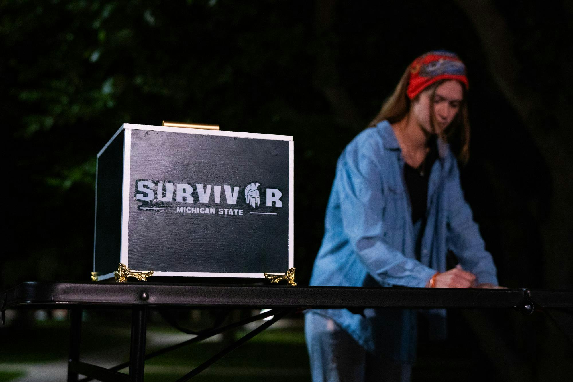 A contestant scribbles down a name for elimination during Survivor: MSU's first tribal council of the season at Erickson Hall on Sep. 8, 2024.