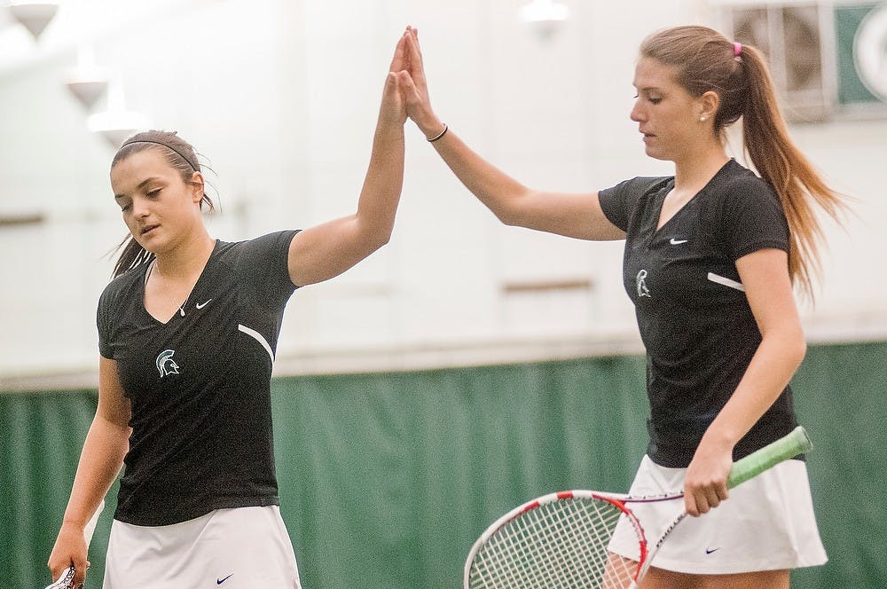 	<p>Sophomore Catherine Parenteau, left, and doubles partner junior Marina Bohrer high five after scoring a point during the tennis match against Nebraska on April 14, 2013, at the <span class="caps">MSU</span> Indoor Tennis Facility. The Spartans lost to the Cornhuskers, 6-1. Natalie Kolb/The State News</p>