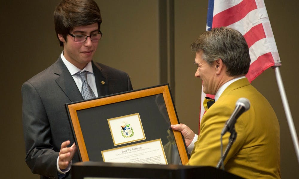 Zeta Psi international president Bath Gillian hands world politics junior Sina Ghobadi, president of the MSU chapter, the official plaque for the fraternity at the Zeta Psi's charter ceremony on Dec. 5, 2015 at Kellogg Center. 