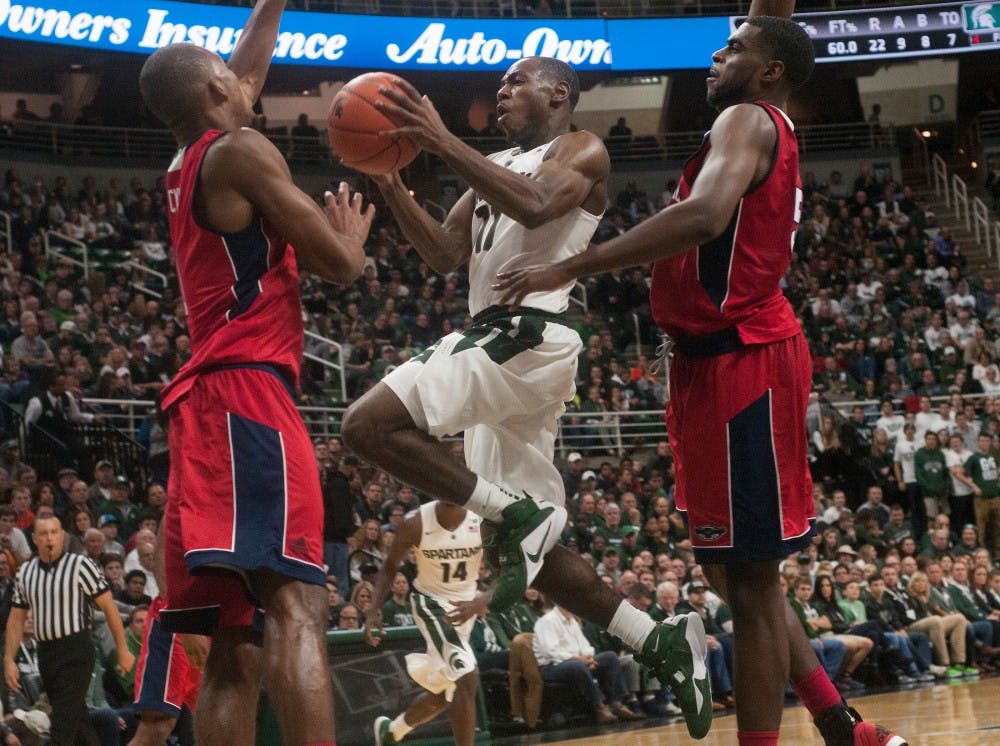 <p>Sophomore guard Lourawls 'Tum Tum' Nairn Jr. attempts a basket despite efforts made by Florida Atlantic forward Jeantal Cylla and forward Matthew Reed, 50, during the first half of the game against Florida Atlantic on Nov. 13, 2015 at Breslin Center. The Spartans defeated the Owls, 82-55.</p>