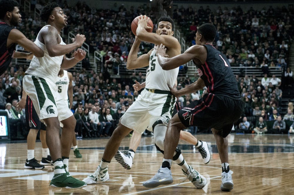 Sophomore forward Kenny Goins (25) looks to pass over Northwestern guard Shawn Occeus (1) during the game against Northeastern on Dec. 18, 2016 at Breslin Center. The Spartans were defeated by the Huskies, 73-81. 
