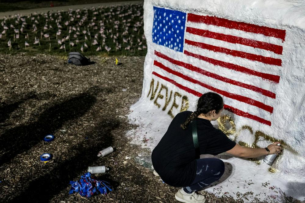 <p>Jazmin Cortes, a junior studying mechanical engineering and a member of MSU College Republicans, spray-paints the words “Never Forget” on The Rock while preparing a 9/11 memorial at Michigan State University in East Lansing, Mich., on Thursday, Sept. 10, 2026. The organizations placed 2,977 American flags around The Rock, one for each victim killed in the 9/11 terrorist attacks.</p>