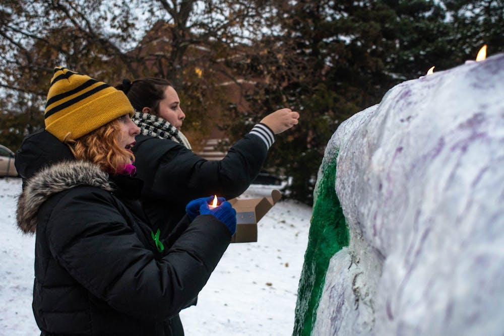 <p>A student places a candle on The Rock on Farm Lane for a candlelight vigil for ASMSU’s Mental Health Awareness Week on Nov. 11, 2019.</p>