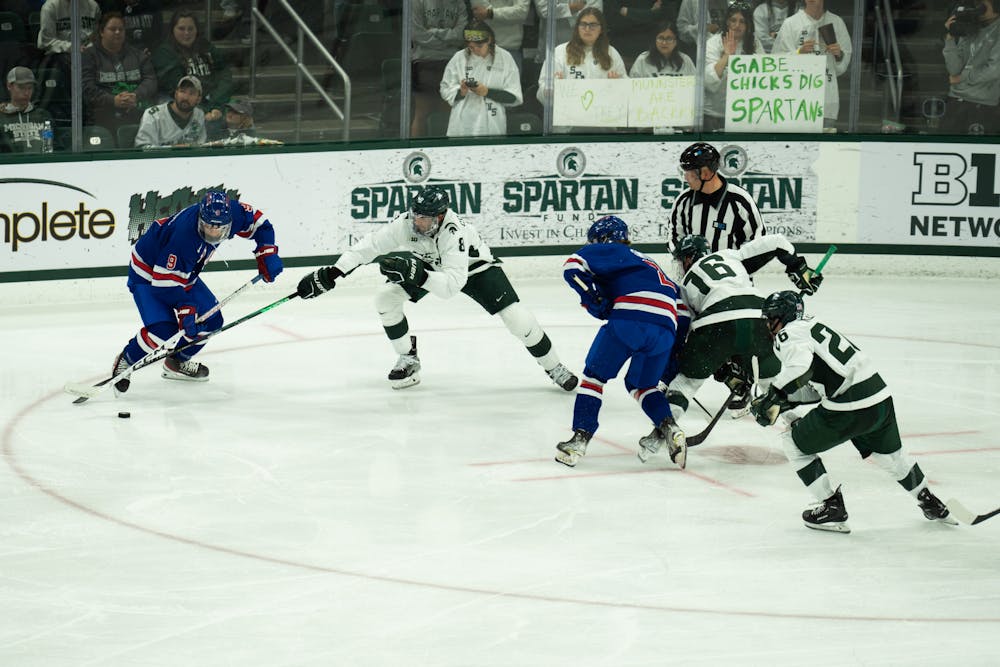 <p>Senior left defense Cole Krygier (8) attempts to regain the puck at Munn Ice Arena on Oct. 1, 2022. The Spartans lost to the USNTDP 4-3.</p>