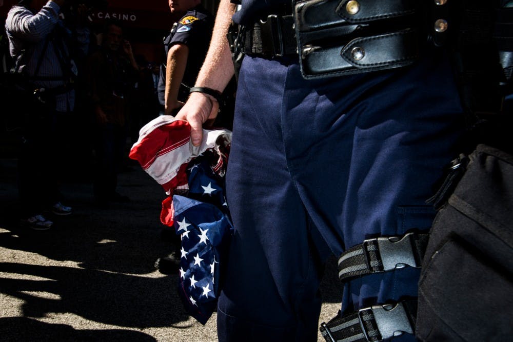 A police officer grasps a burned American flag on July 20, 2016, the third day of the Republican National Convention, in Cleveland, Ohio. The flag was burned by a protest group called the Revolutionary Communist Party.