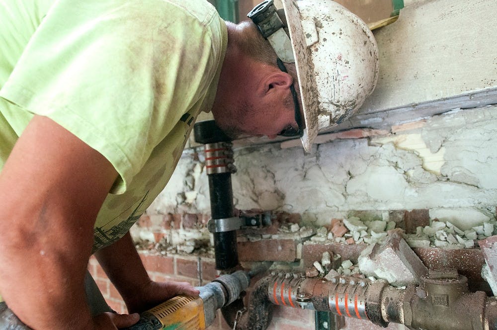 	<p>Perry, Mich., resident Ken Roy removes bricks from a wall on July 23, 2013, at Landon Hall. Construction is expected to be completed in September 2014. Weston Brooks/The State News</p>