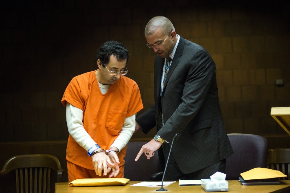 Former MSU employee Larry Nassar, left, converses with his defense attorney, Matt Newburg, during a preliminary examination conference on March 2, 2017 at 55th District Court in Mason, Mich. Nassar's preliminary examination was deferred to May 12, 2017.