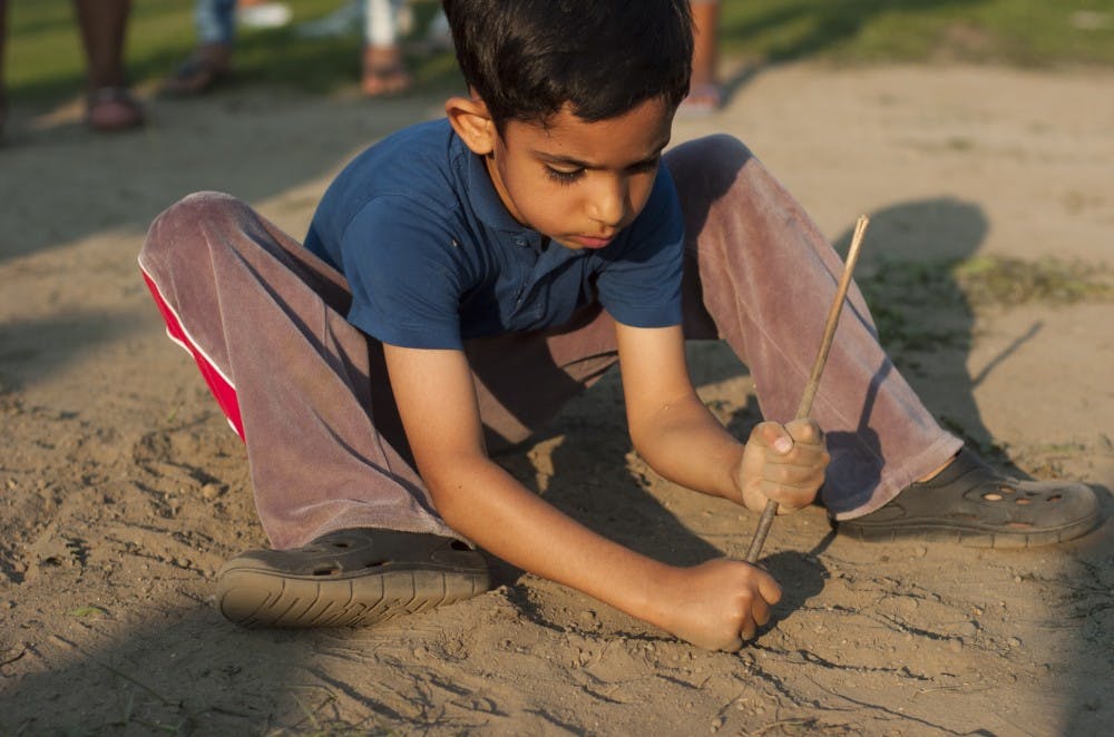 <p>East Lansing resident Alireza Eslami, 6, plays in the dirt on Sept. 1, 2015, during Sparticipation at Cherry Lane Field. Elsa was there with his father, who is a faculty member at Michigan State. </p>