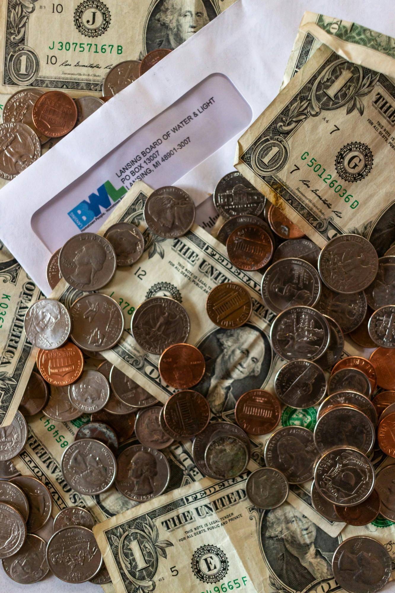 Coins, dollar bills, and a Lansing Board of Water and Light bill photographed on April 7, 2020.