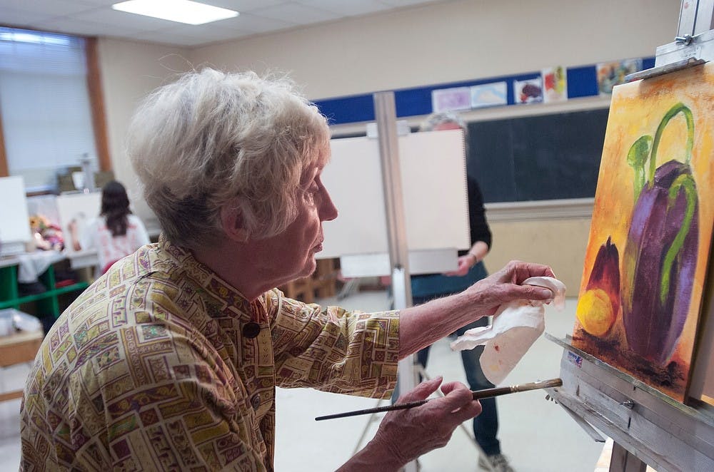 <p>Lansing resident Nora Polley dabs her artwork during a drawing and painting class Nov. 6 2013, at the Bailey Community Center. Polley said she has always wanted to learn to paint and found a great teacher at the community center. Olivia Dimmer/The State News</p>