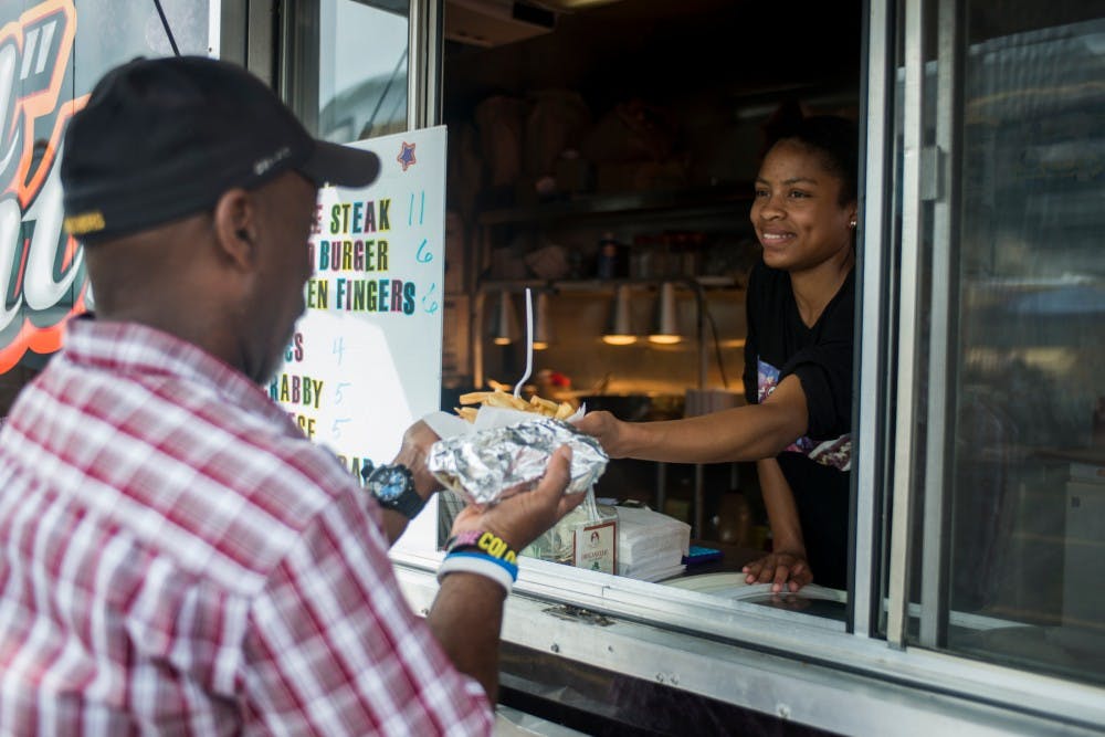 Philadelphia, Pa. resident Bashianta Anderson hands an order of fries to Boston, Mass. resident Howard Powell on July 26, 2016, the second day of the Democratic National Convention, at Lil' Trent's Grille food truck in Philadelphia.