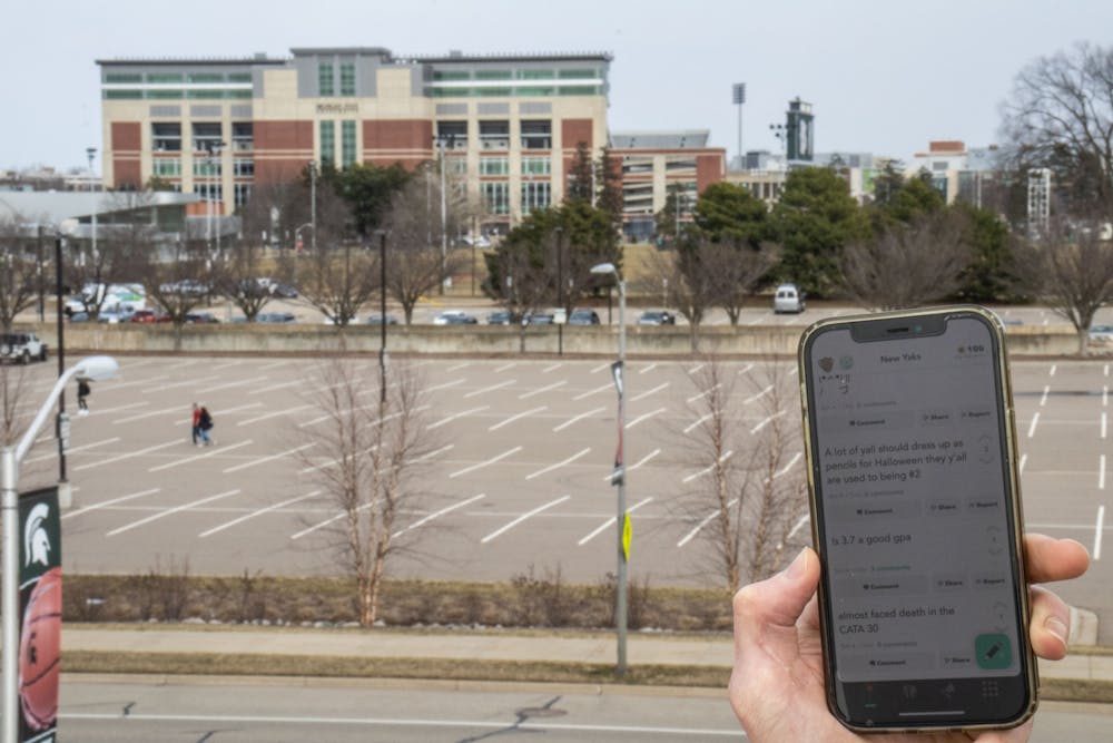 Photo illustration of student on YikYak with Spartan Stadium in the background taken on March 21, 2022.