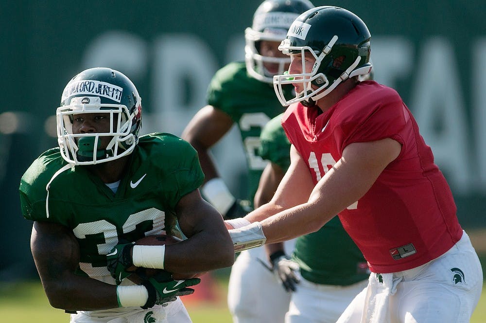 	<p>Sophomore quarterback Connor Cook hands off the ball to junior running back Jeremy Langford Aug. 19, 2013, at the practice field outside Duffy Daugherty Football Building. Julia Nagy/The State News</p>