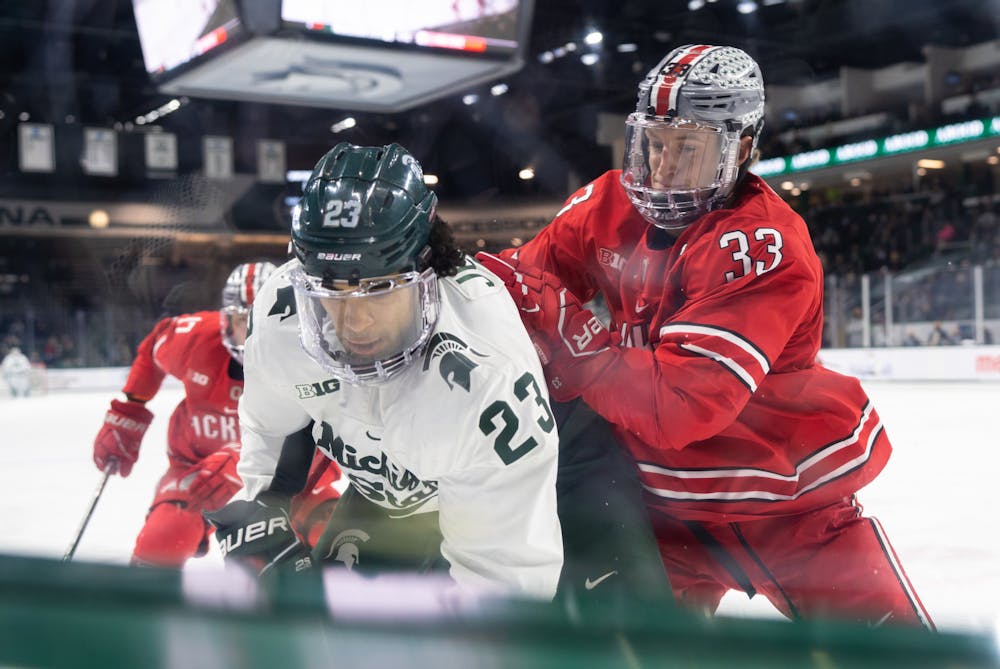 <p>Junior forward Jagger Joshua (23) fights for the puck while being grabbed by Ohio State&#x27;s graduate defenseman Will Riedell in the first period. The Spartans fell to the Buckeyes, 4-1, at Munn Ice Arena on Jan. 21, 2022. </p>