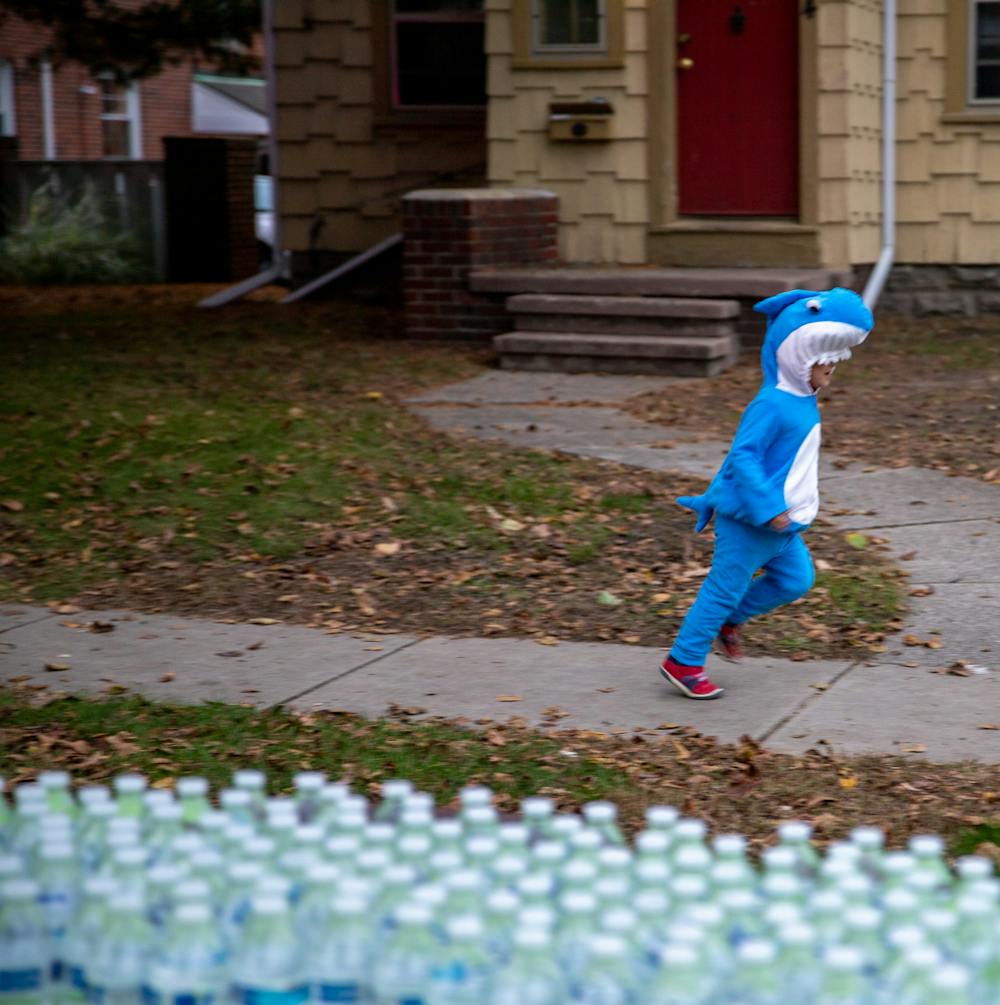 <p>M.A.C. Avenue and surrounding streets in East Lansing were closed off for Safe Halloween on Oct. 27, 2021. Shown is a table of water bottles and a shark running in the background. </p>