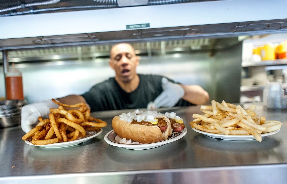 	<p>Kevin Gelispie, a cook at the Leo&#8217;s Coney Island, serves onion rings, hot dogs and French fries on June 6, 2013, at the restaurant&#8217;s East Lansing location, of 333 Albert Ave. July is National Hot Dog Month. Justin Wan/The State News</p>