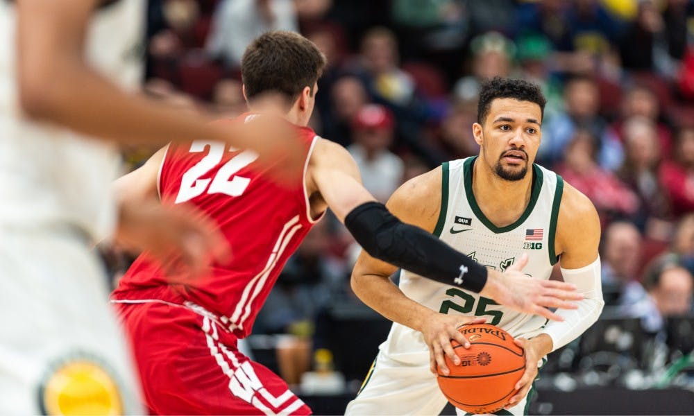 Senior forward Kenny Goins (25) is defended by Wisconsin's Ethan Happ. The Spartans beat the Badgers, 67-55, at the United Center on March 16, 2019.