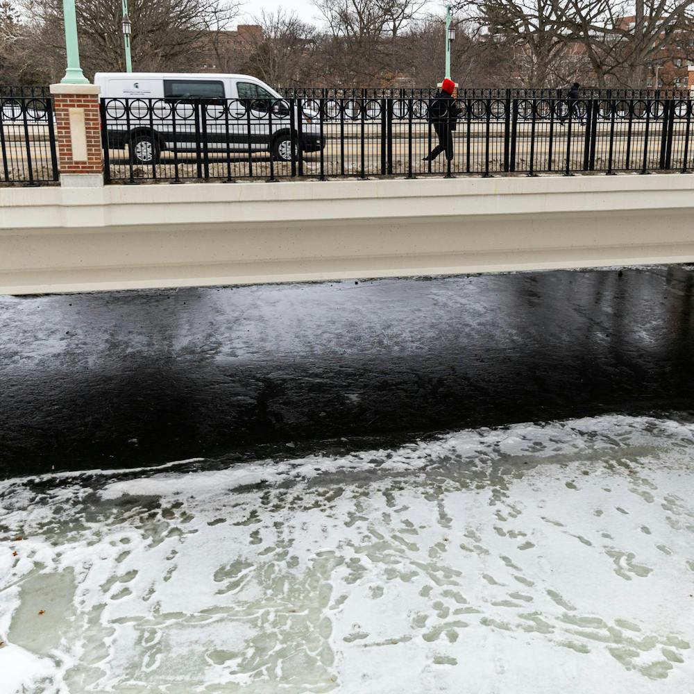 The iced over Red Cedar River sits with many student footprints under Farm Ln in East Lansing, MI on Feb. 11, 2026.