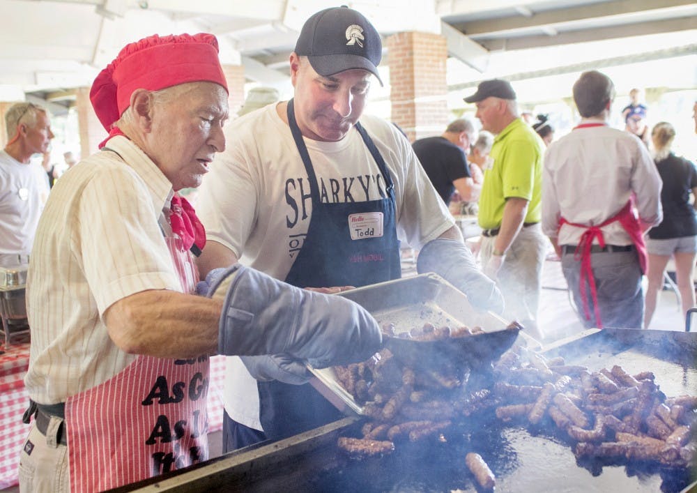 Chief apple and sausage maker, and East Lansing resident Omero Iung, left, and Todd Selin, a Lansing resident, prepare a batch of sausages during Pancakes-in-the-Park at the pavilion in East Lansing’s Patriarche Park on Sunday.