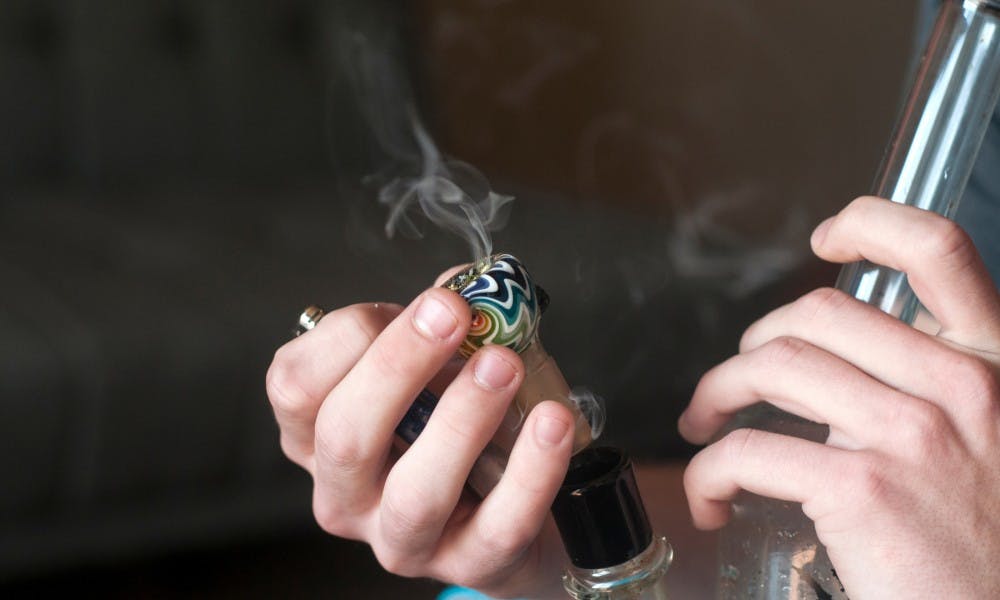 <p>Sophomore and secondary education major Lucas smokes a bong on Sept. 16, 2015 in his Clippert Street apartment in Lansing. Lucas has a license to use medical marijuana and smokes to alleviate pain associated with scoliosis. Catherine Ferland/The State News</p>