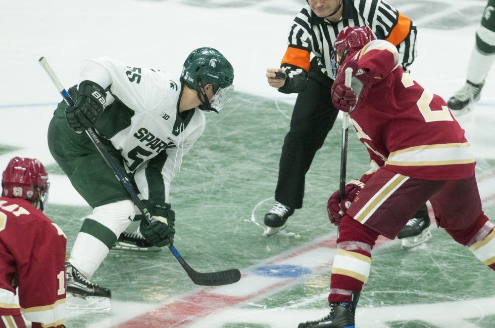 From left, freshman forward Patrick Khodorenko (55) prepares to take a face off against Denver forward Matt Marcinew (23) during the game against Denver on Oct. 21, 2016 at Munn Ice Arena.  The Spartans were defeated by the Pioneers, 2-1. 