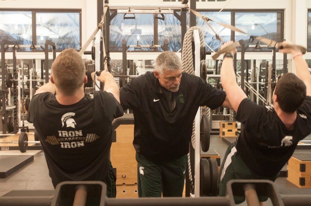  Head strength and conditioning coach Ken Mannie works with students on April 6, 2016 during weight lifting practice at Duffy Daugherty Building  Students were on their second work out of the day.