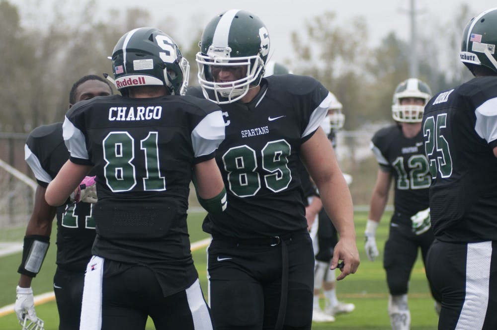 <p>Sophomore wide receiver Nick Chargo, 81, high-fives senior defensive lineman Devin Schlossberg during the second quarter of the MSU Club football game against the Ohio State club team on Oct. 4, 2015 at Hope Sports Complex, 5801 N Aurelius Road, in Lansing.  The MSU Club football team was started about a year ago and has just over 50 players. </p>