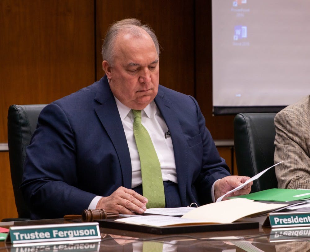 <p>Interim John Engler looks over some documents during the public comment section of the meeting Dec. 14, 2018 at the Hannah Administration Building.</p>