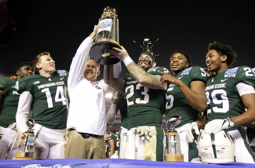 Michigan State coach Mark Dantonio holds up the Holiday Bowl trophy as he and his players, quarterback Brain Lewerke, left, Chris Frey, third from right, Hunter Rison, second from right, Shakur Brown, celebrate a 42-17 win against Washington State at SDCCU Stadium in San Diego on Thursday, Dec. 28, 2017. (Hayne Palmour IV/San Diego Union-Tribune/TNS)